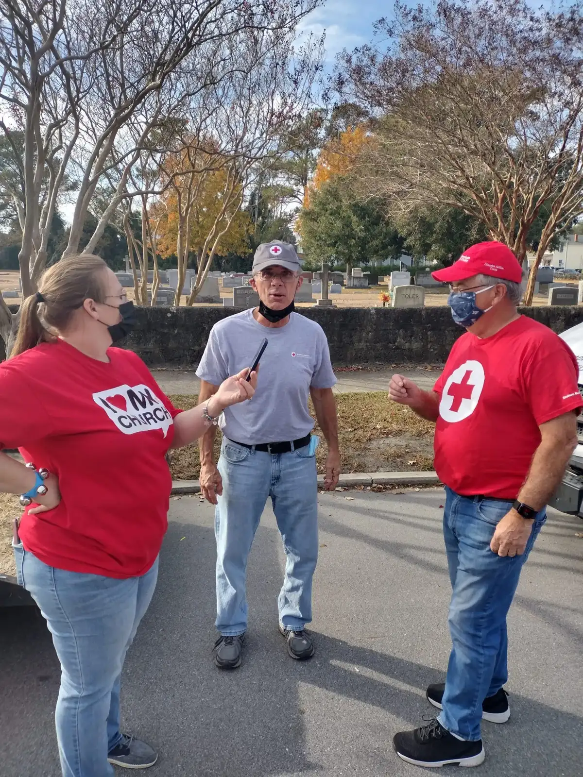 Three volunteers talking together outdoors during a New Vision Ministries community service event