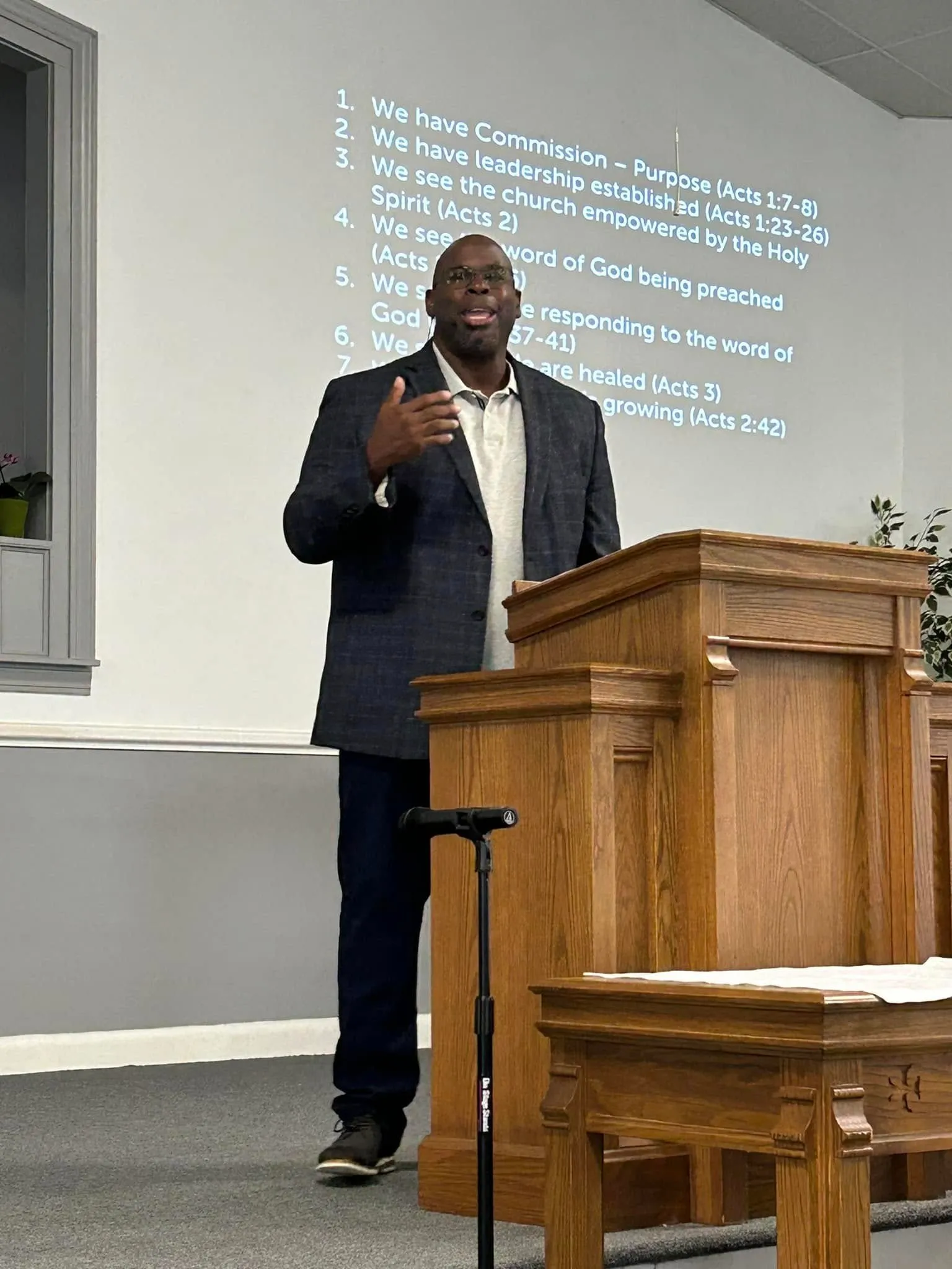 Pastor Baldwin preaching at the pulpit with a teaching outline projected behind him